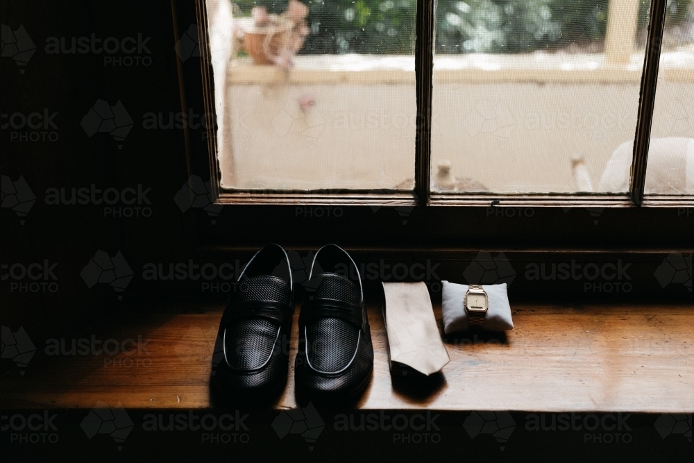 Wedding accessories for husband lined up on window sill shoes tie and watch - Australian Stock Image