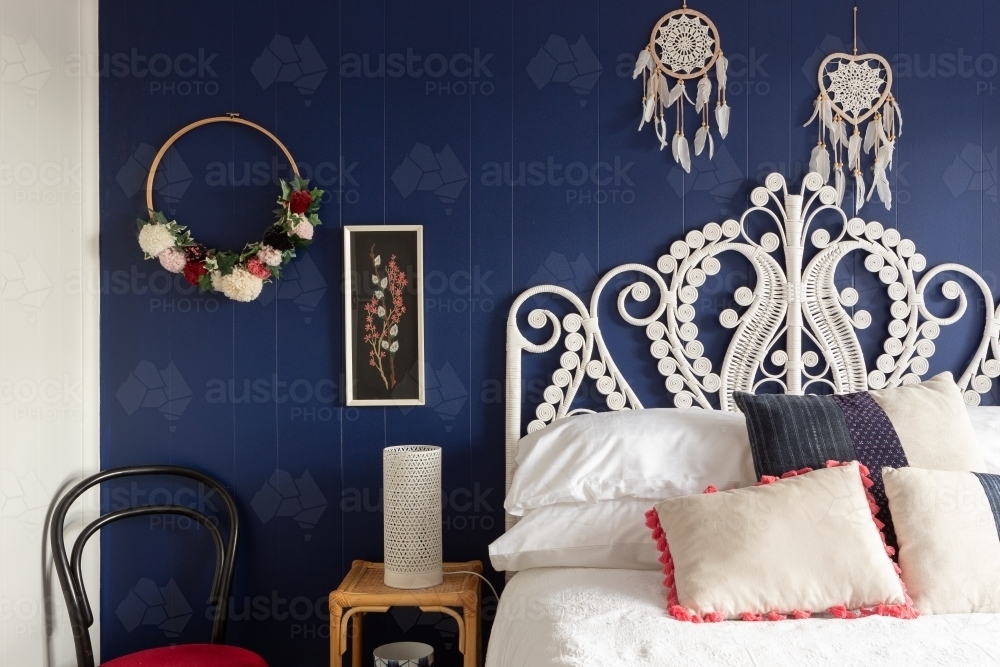 White cane bed head against dark blue wall - Australian Stock Image