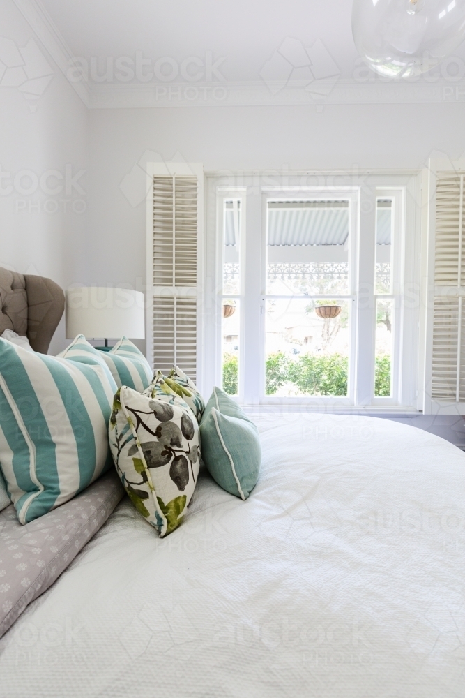 White shutters and blue fabric cushions in a beautiful bedroom interior - Australian Stock Image