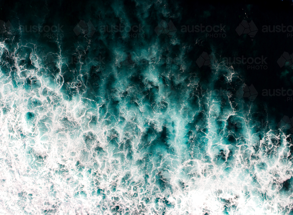 White wash and aqua patterns illuminate a dark ocean - Australian Stock Image