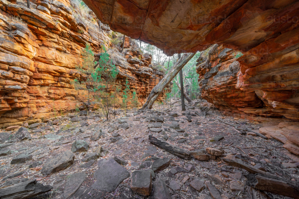 Wide angle view of rock overhang at the base of a rocky gorge - Australian Stock Image