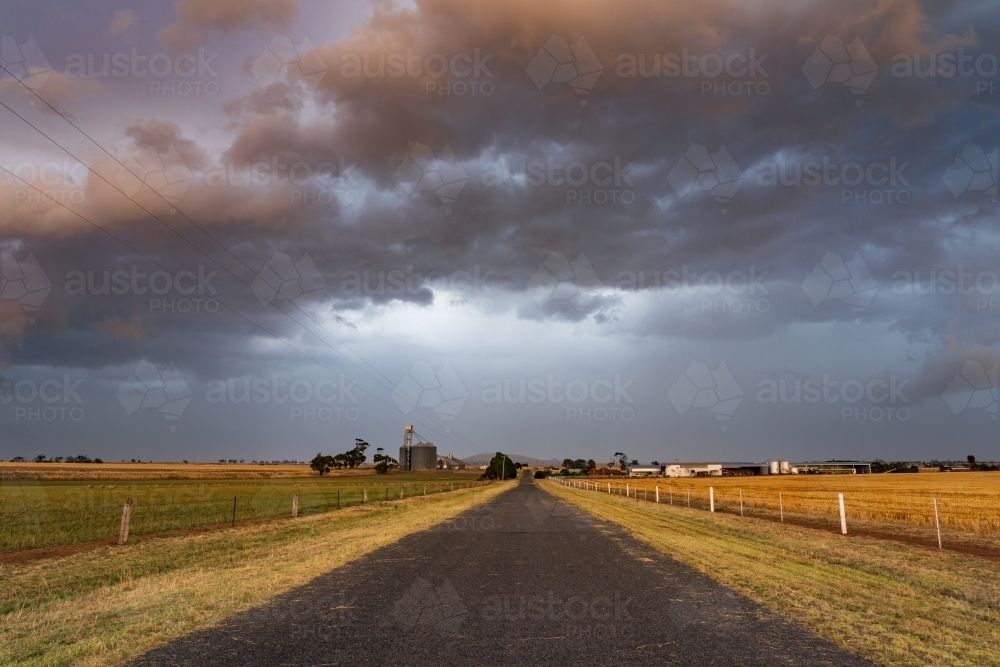 Wide angled view of a colourful dramatic stormfront over a country road - Australian Stock Image