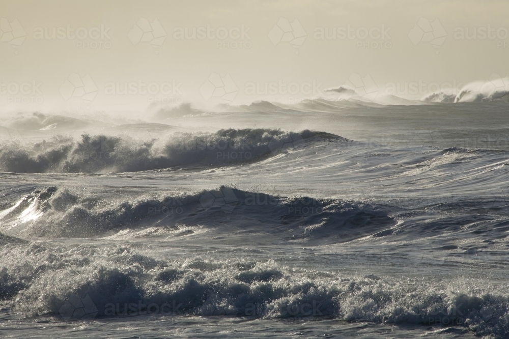 Wild lines of surf in silvery backlight and sea haze - Australian Stock Image