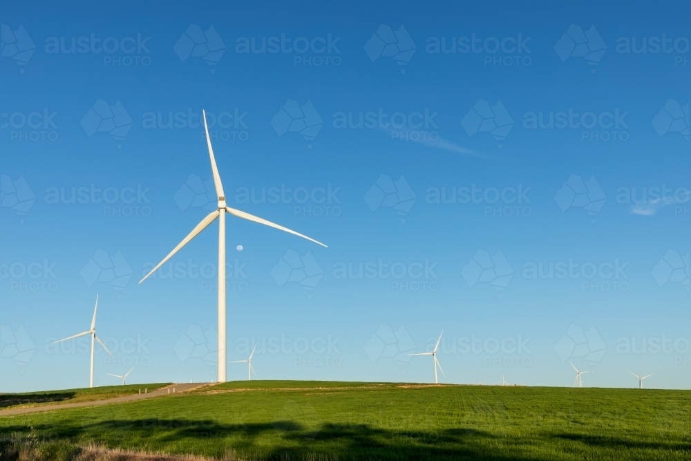 wind turbines against blue sky and green farmland - Australian Stock Image