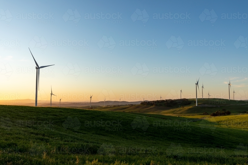 wind turbines in rolling farmland in late afternoon light - Australian Stock Image