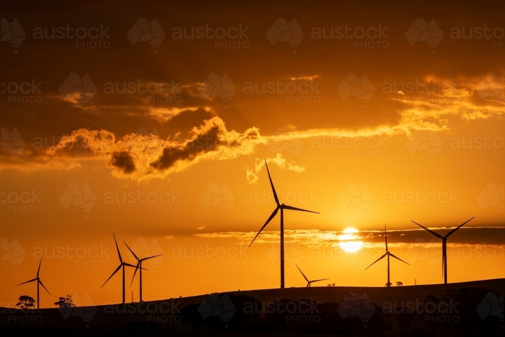 wind turbines silhouetted against setting sun - Australian Stock Image