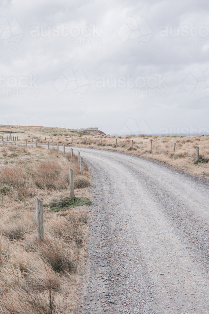 Winding, gravel track with posts and dry, summer grasses - Australian Stock Image