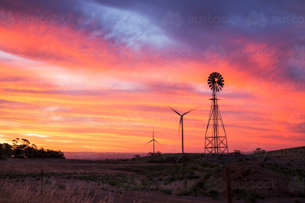 Windmill and wind turbines silhouetted against sunset - Australian Stock Image