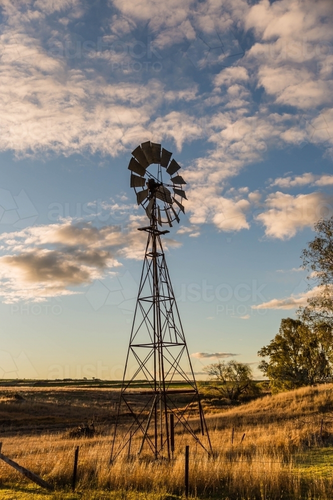 Windmill on farm with cloudy sky - Australian Stock Image