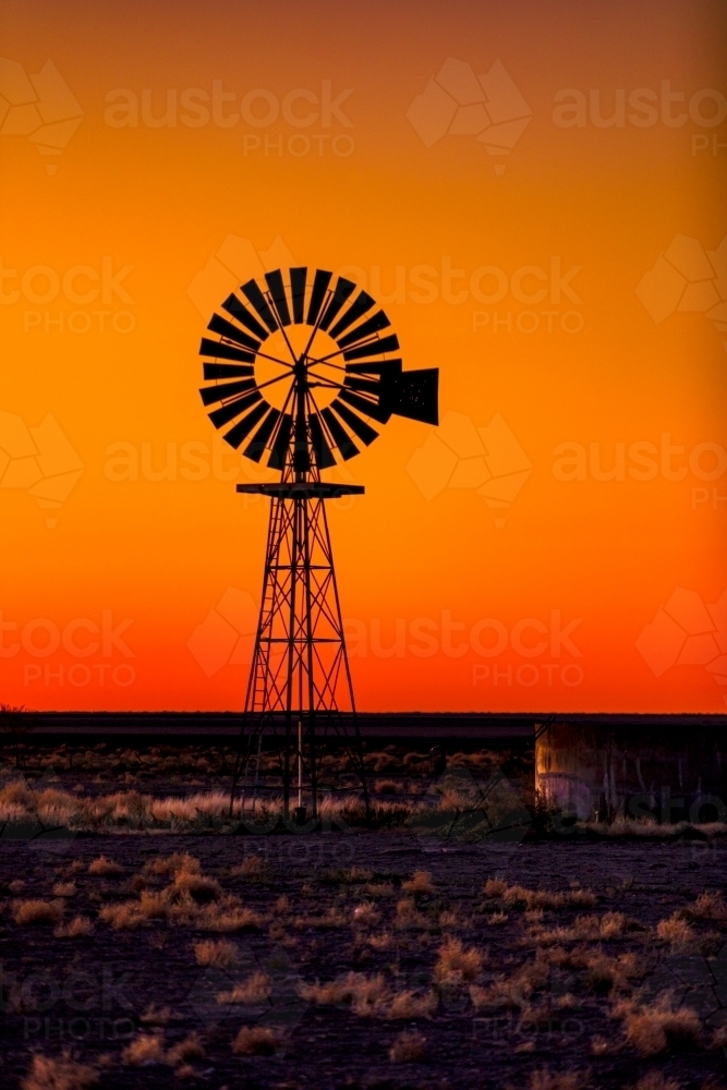 Windmill silhouette against an orange Sunset - Australian Stock Image