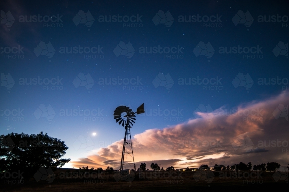 Windmill silhouette in the night as a storm approaches - Australian Stock Image