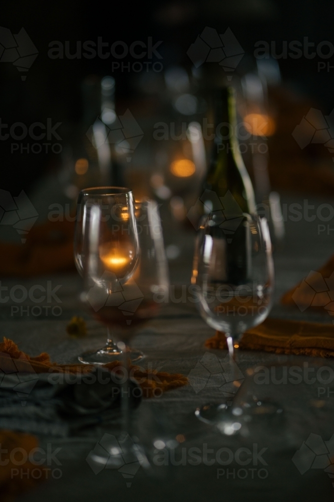 Wine glasses and a bottle of wine set on the table in a dimly lit scene - Australian Stock Image