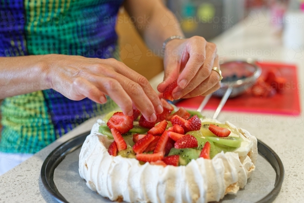 Woman adding strawberries on top of the traditional Australian Pavlova - Australian Stock Image