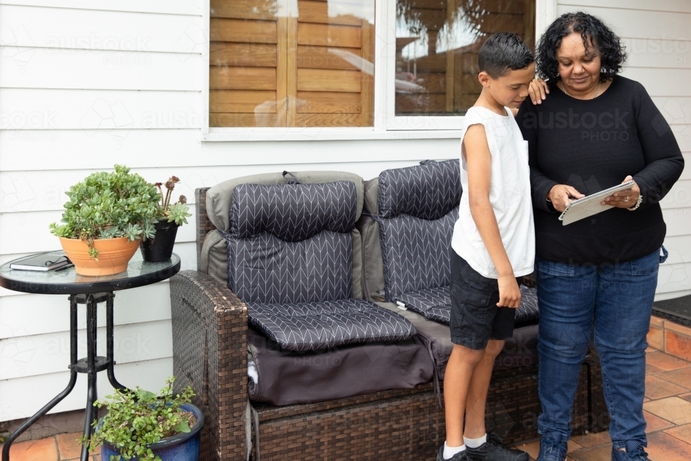 Woman and boy looking at a mobile tablet on porch - Australian Stock Image