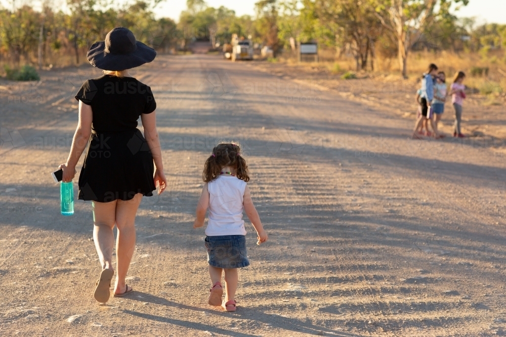Woman and child walking away on a corrugated outback road - Australian Stock Image