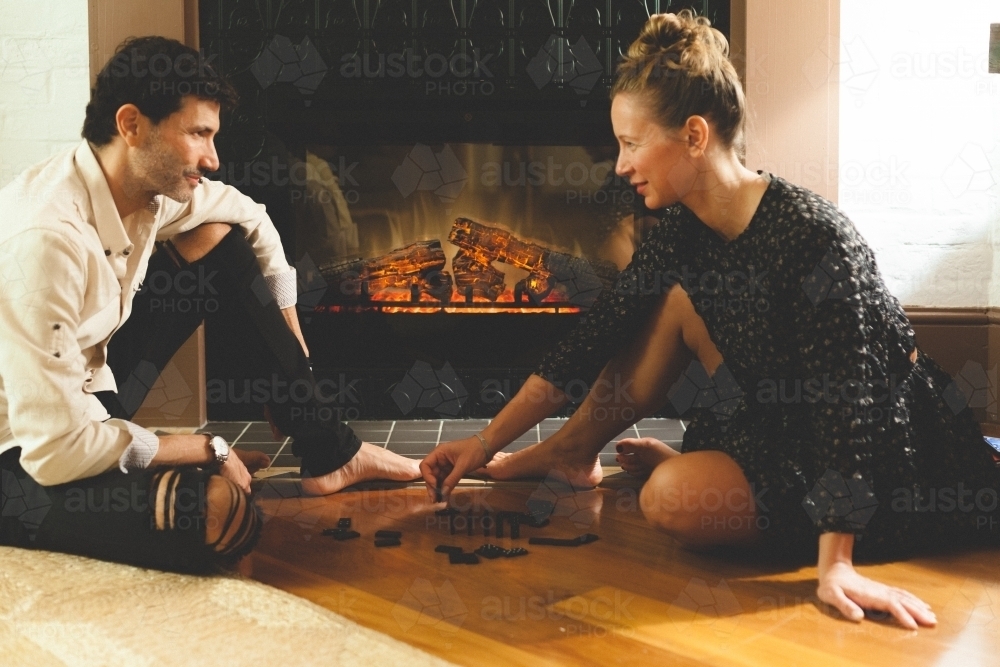 Woman and man playing dominoes by the fireplace - Australian Stock Image