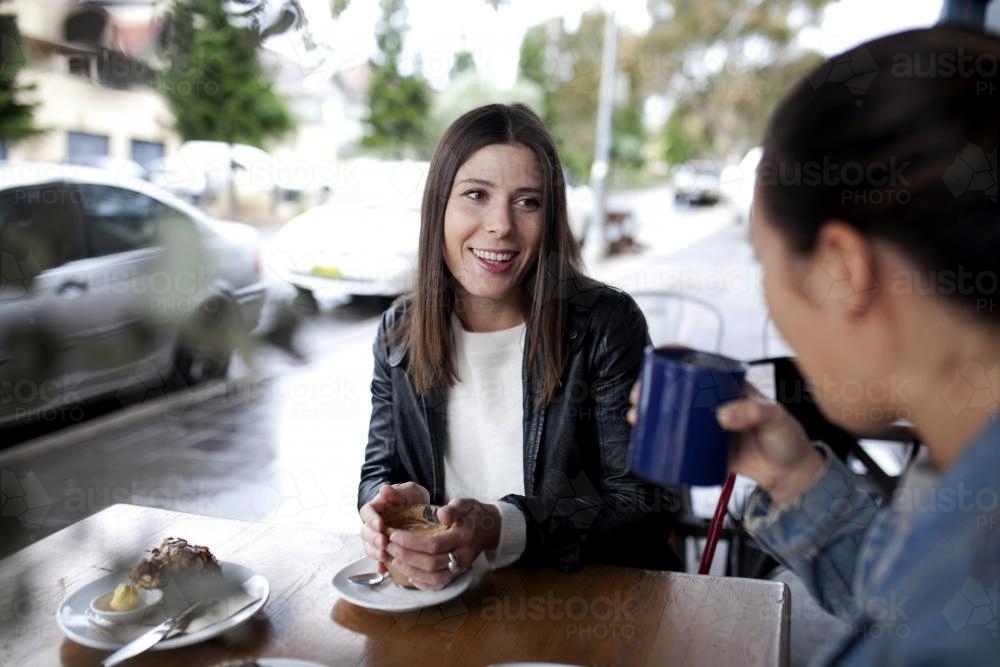 Woman at cafe drinking coffee with a friend - Australian Stock Image