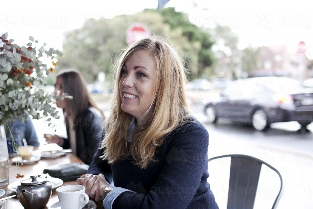 Woman at cafe smiling and looking to the side - Australian Stock Image