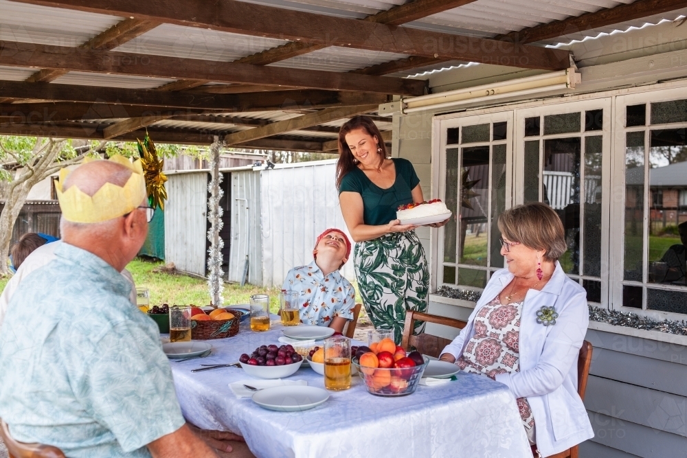 Woman bringing out pavlova for dessert at family Christmas lunch party - Australian Stock Image