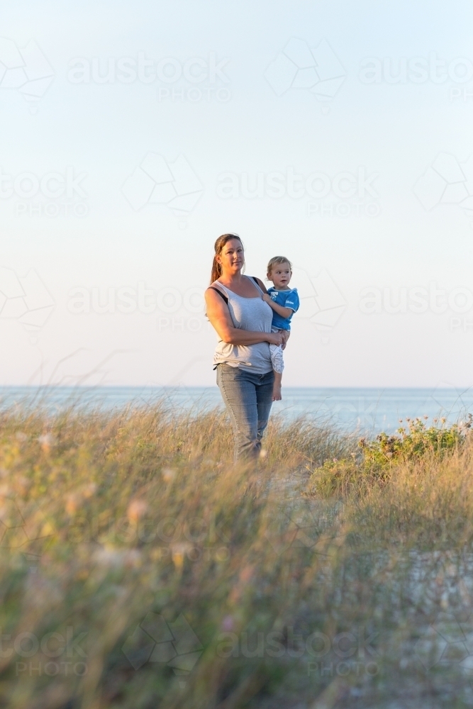 Woman carrying child on her hip near the sea - Australian Stock Image