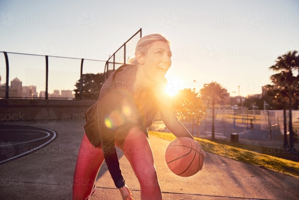 Woman dribbling basketball in the sun - Australian Stock Image