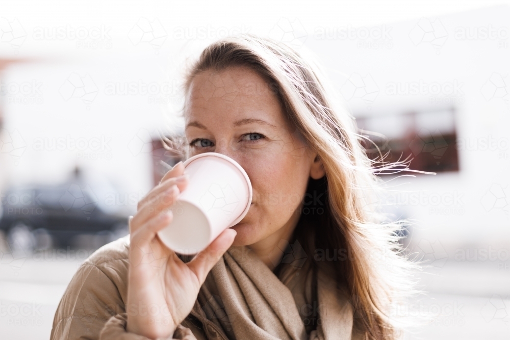 Woman drinking from a coffee cup with urban background - Australian Stock Image