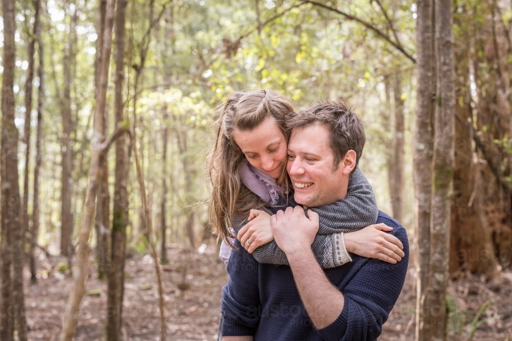 Woman embracing man from behind around neck lovingly - Australian Stock Image