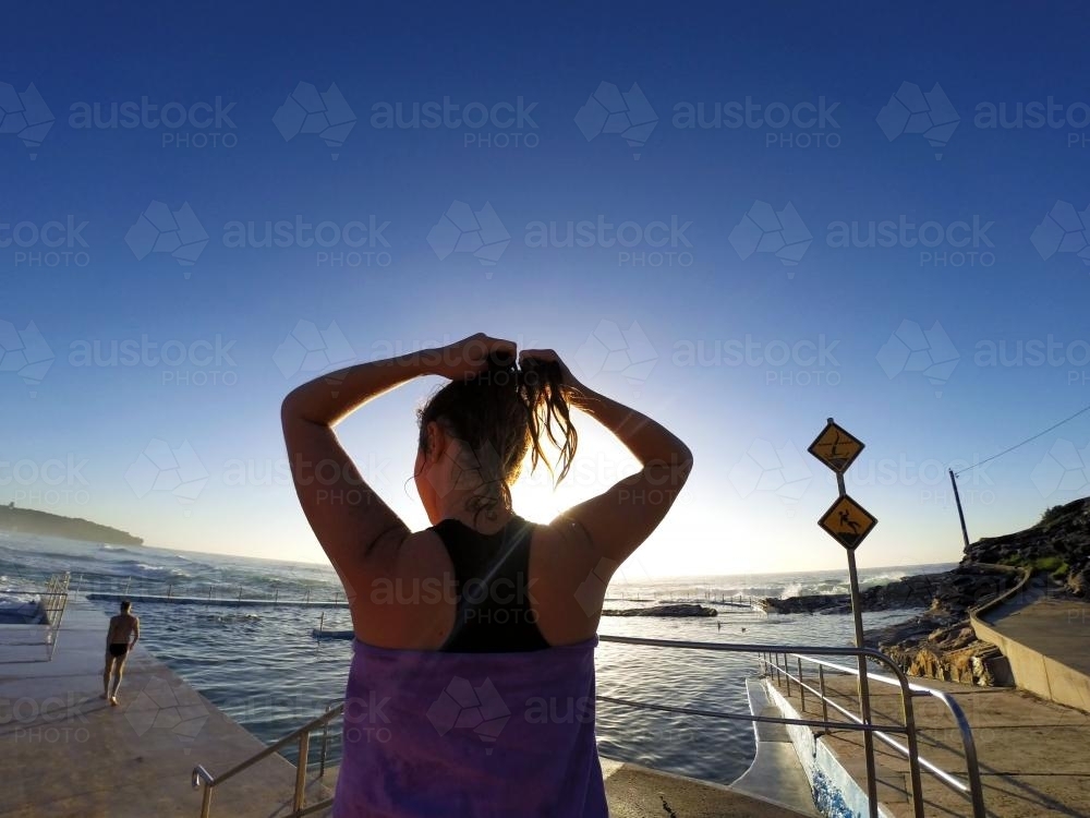 Woman fixing hair after ocean pool swim - Australian Stock Image