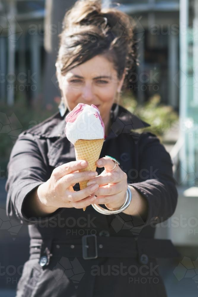 Woman holding out an ice cream cone - Australian Stock Image