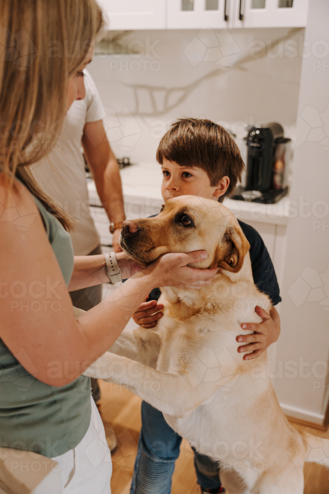 Woman holding the face of her pet dog with family - Australian Stock Image