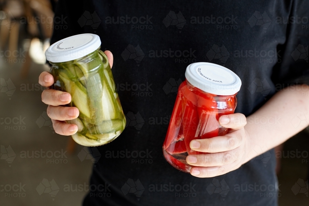 Woman holding two jars of homemade pickles - Australian Stock Image