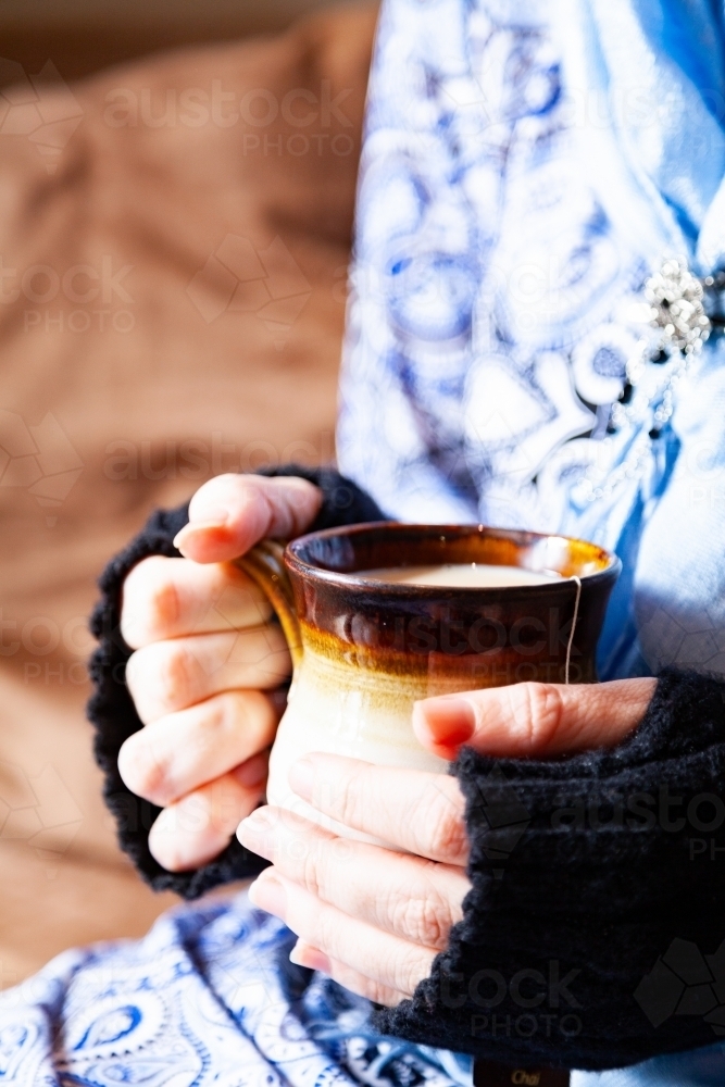 Woman holding warm mug of chai tea in winter - Australian Stock Image