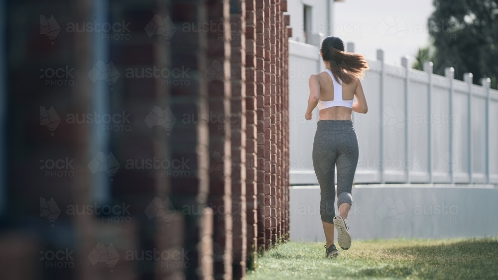 Woman in active wear running for morning exercise - Australian Stock Image