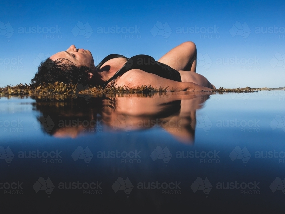 Image Of Woman In Black Bathing Suit Posing On Waters Edge In Calm Ocean Austockphoto