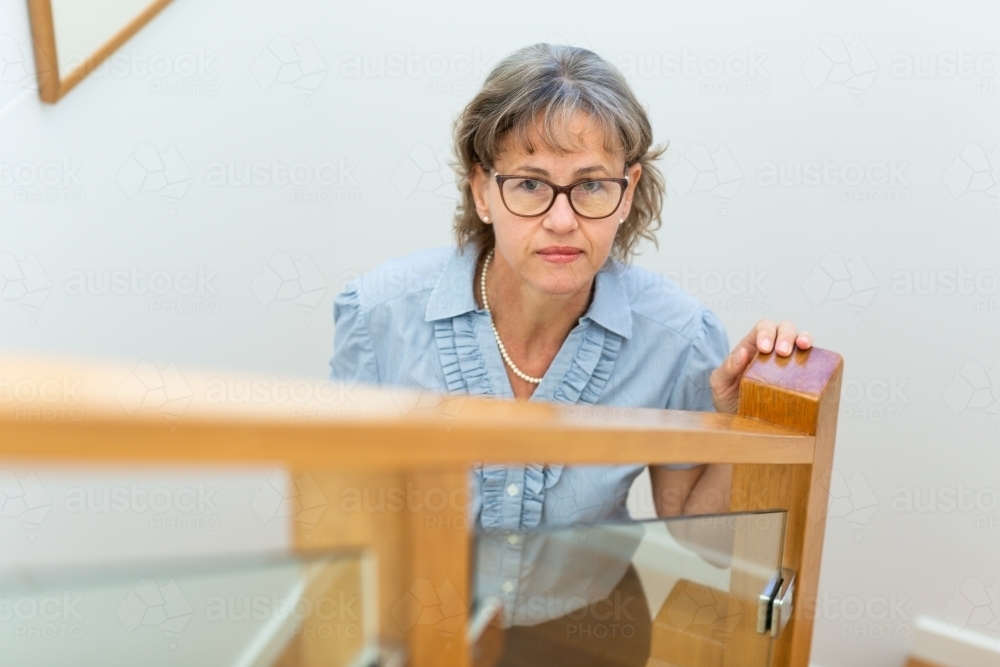 Woman in her 50s looking up from stairwell - Australian Stock Image