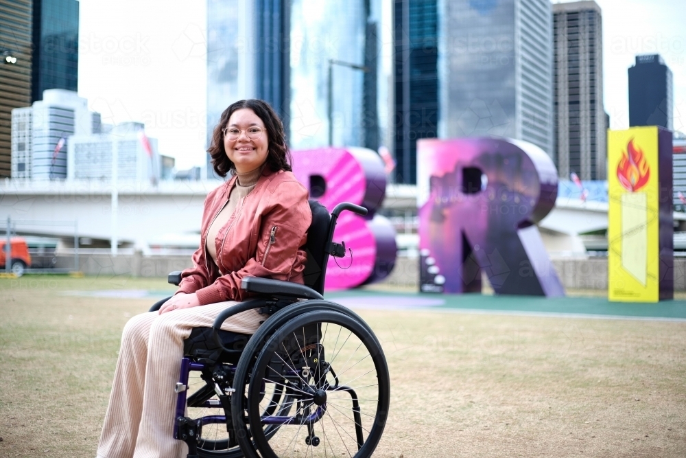 Woman in wheelchair in front of Brisbane sign - Australian Stock Image