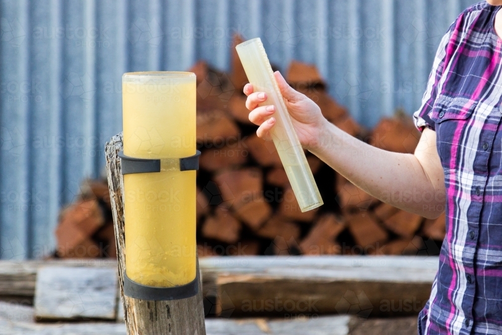 Woman measuring rainfall in farm rain gauge - Australian Stock Image