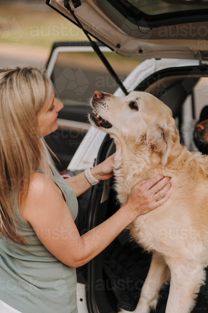Woman petting her dog in the car boot. - Australian Stock Image