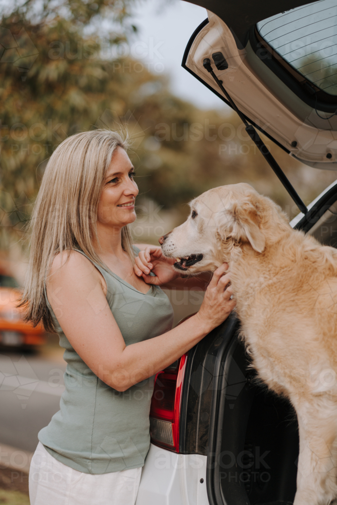 Woman petting her dog in the car boot. - Australian Stock Image