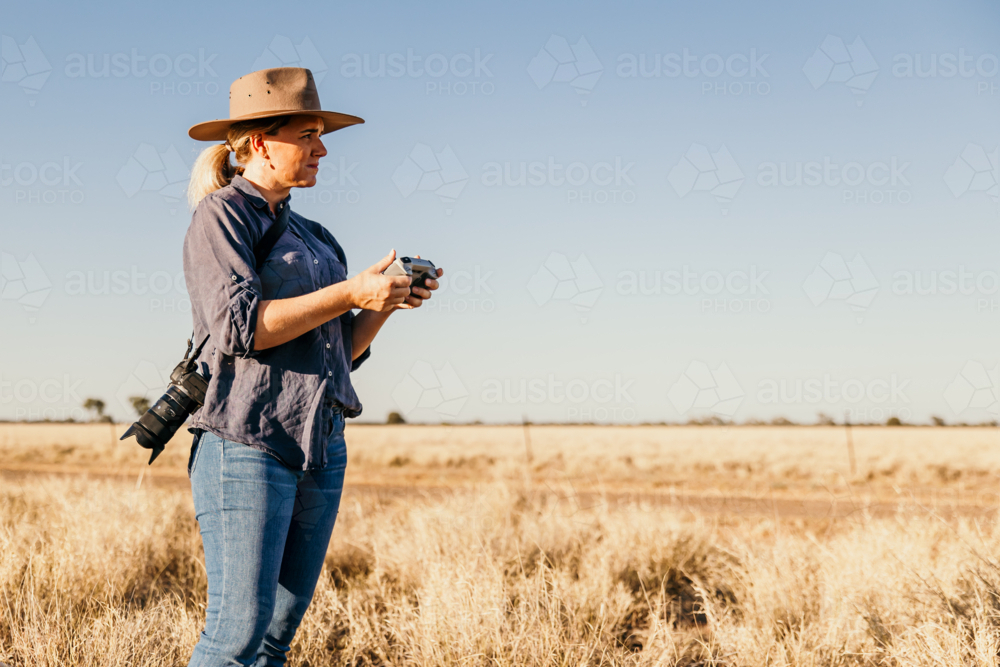 Woman photographer looking forward while holding drone controller - Australian Stock Image