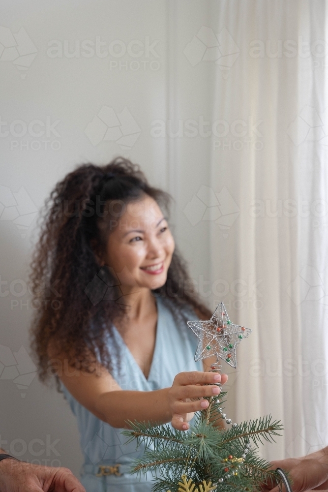 Woman placing star on Christmas tree - Australian Stock Image