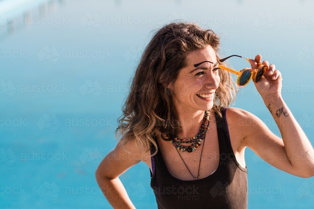 woman putting on sunglasses in the bright light - Australian Stock Image