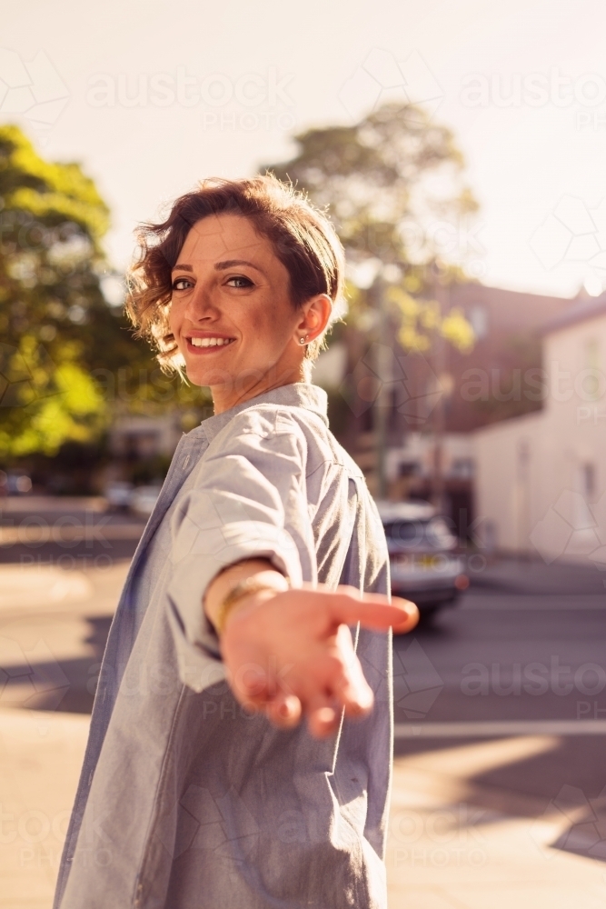 woman reaching back with hand out - Australian Stock Image