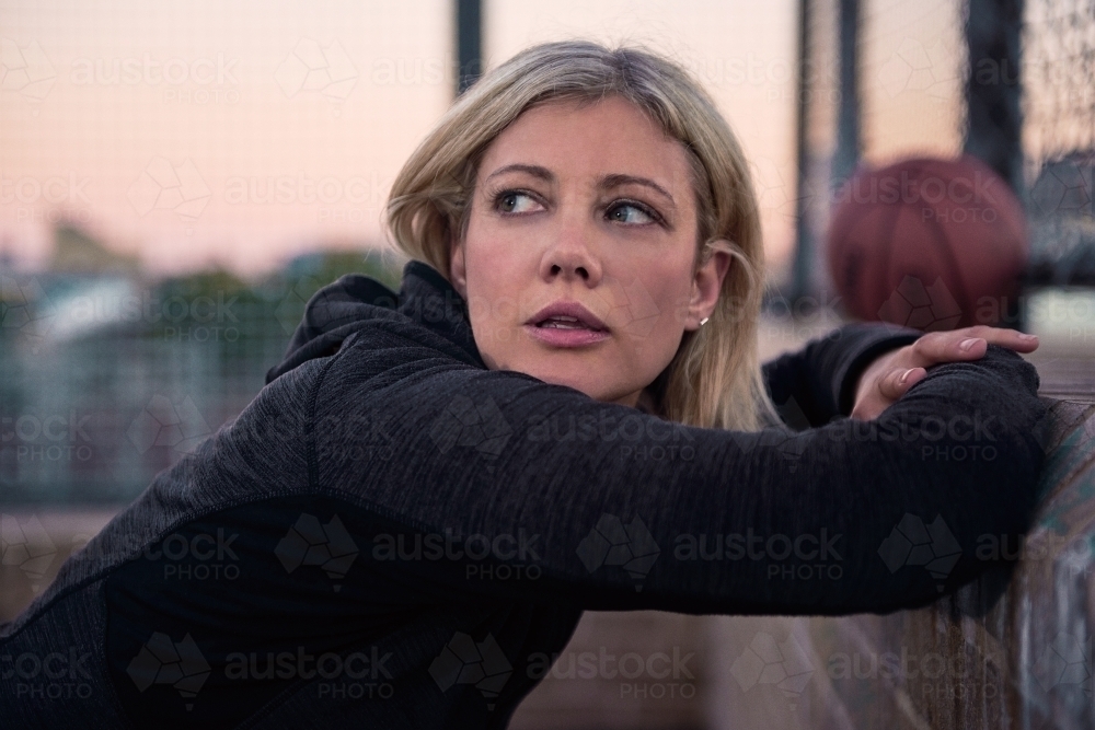 Woman resting stretching on basketball court - Australian Stock Image