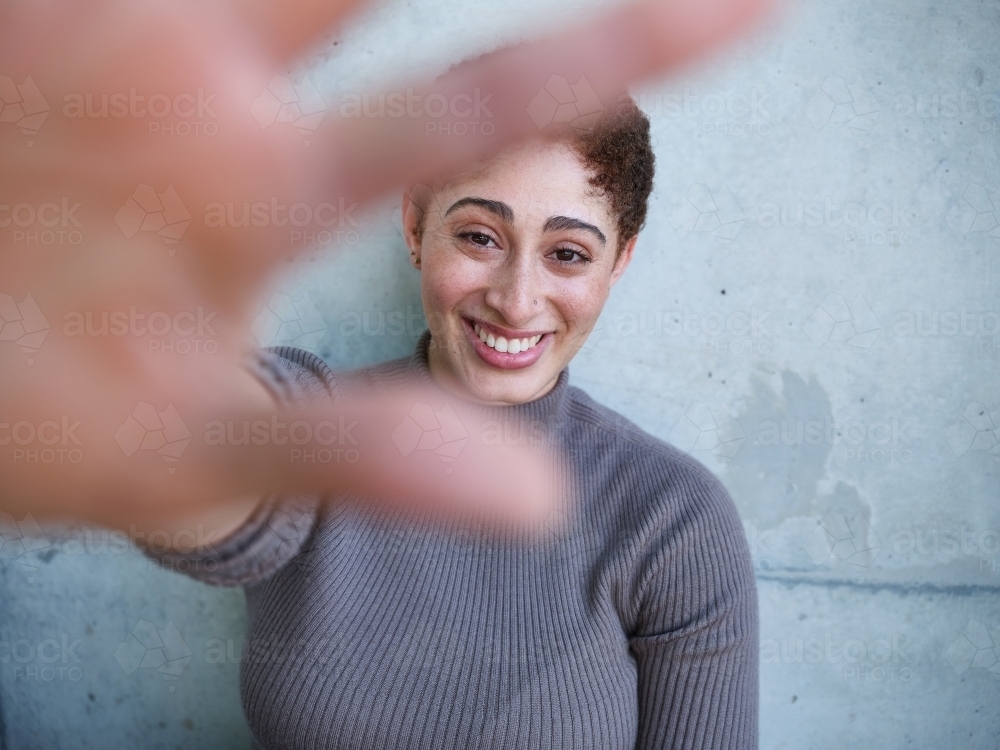 Woman sitting against a concrete wall reaching out - Australian Stock Image