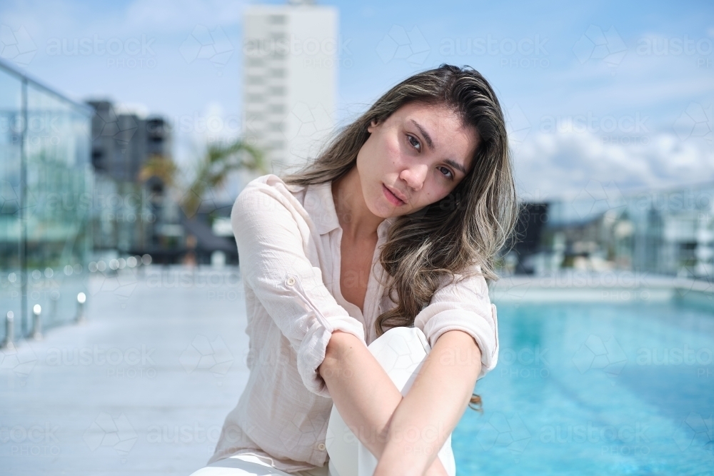 Woman sitting beside rooftop pool - Australian Stock Image