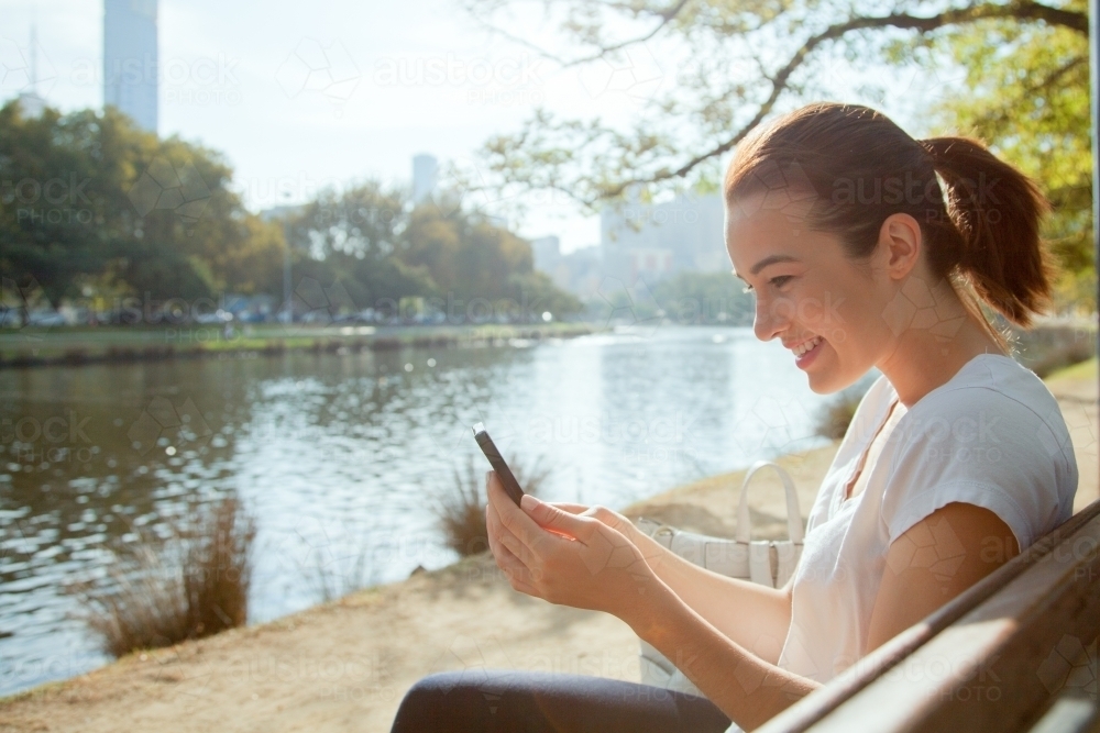 Woman Sitting by the Yarra River and Texting - Australian Stock Image