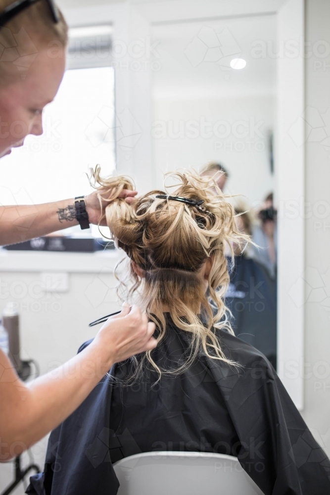 Woman sitting in chair getting hair done at hairdressing salon - Australian Stock Image