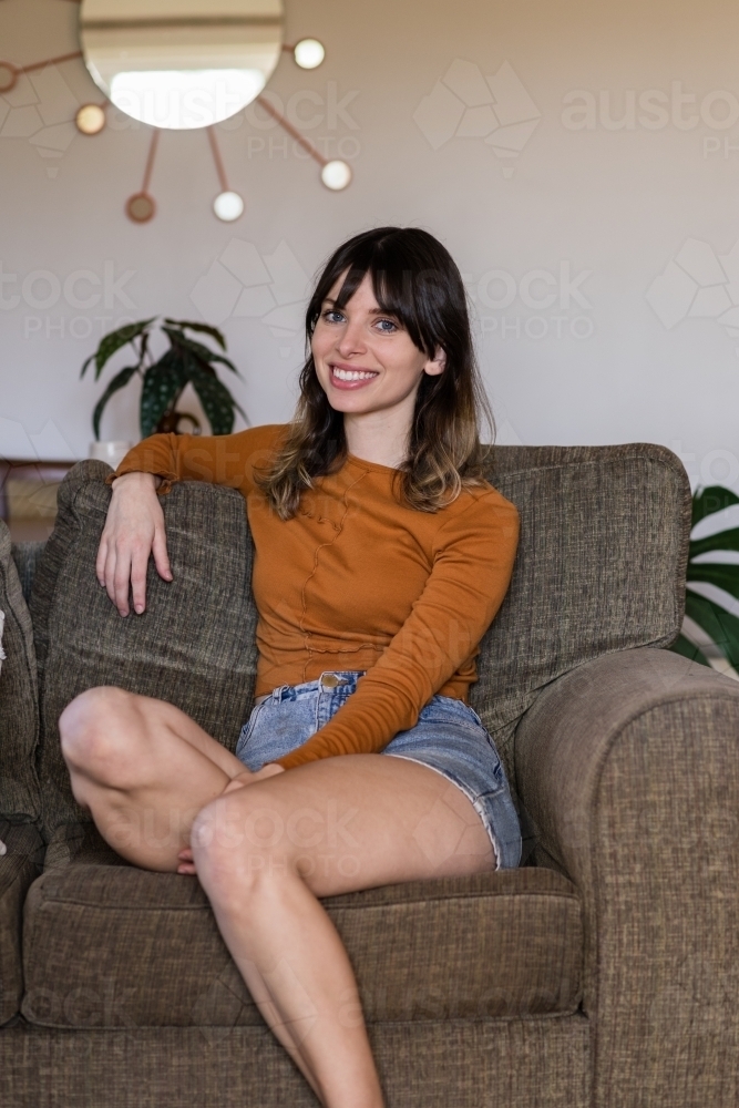 woman sitting on sofa at home - Australian Stock Image