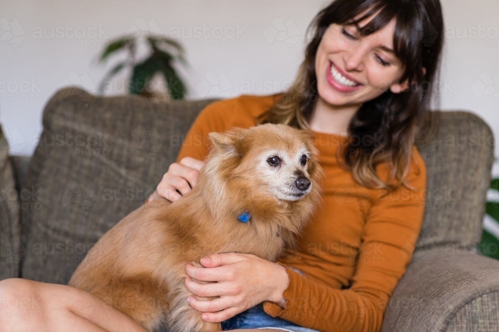 woman sitting on sofa with her little dog - Australian Stock Image